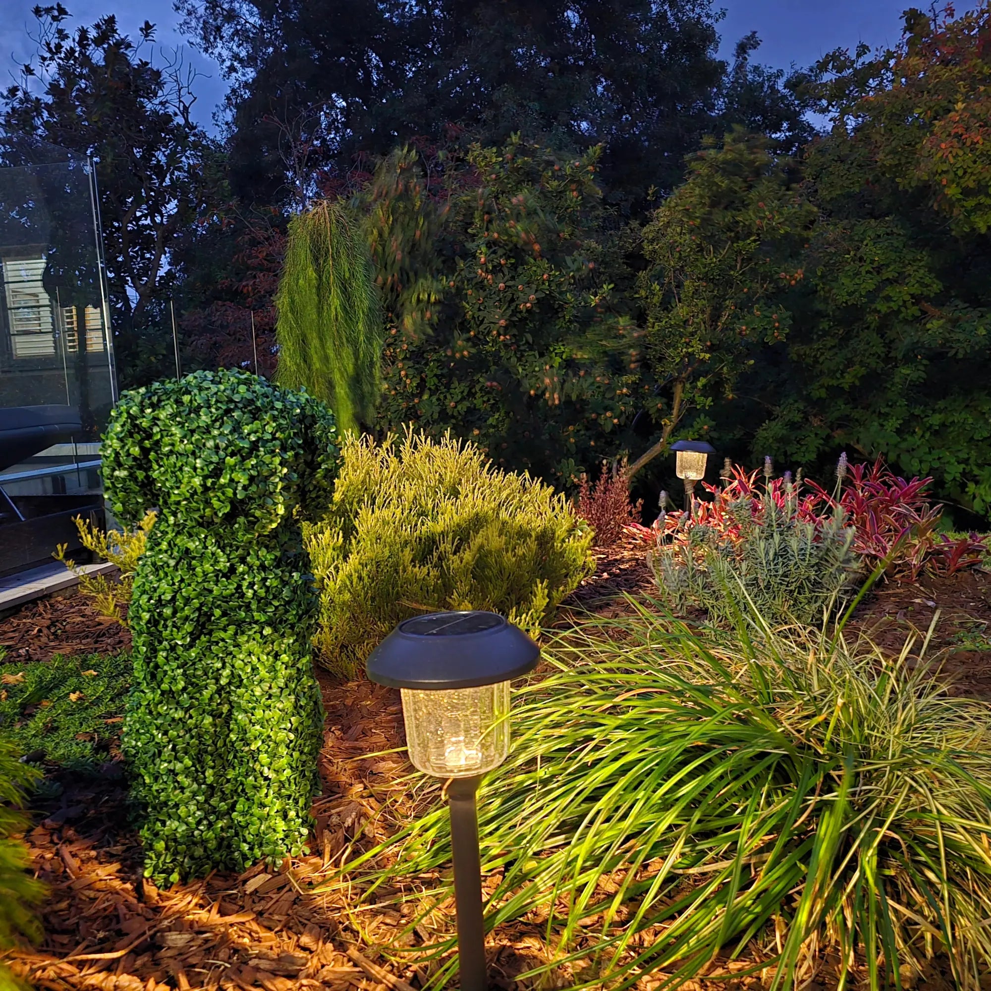 Night view of UV resistant artificial topiary dog in modern backyard