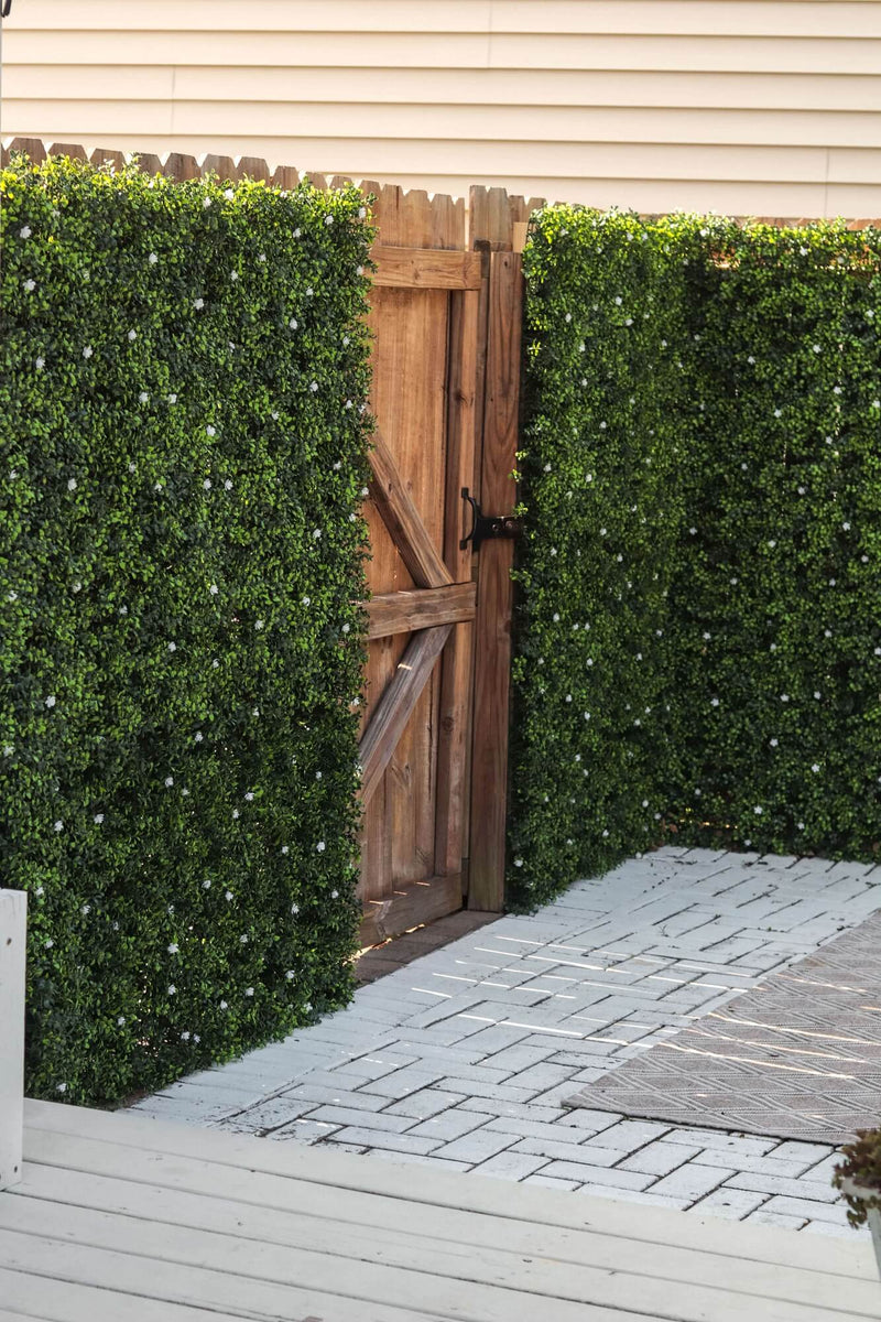 Artificial Boxwood Mat with Faux Flowers Installed Outdoors onto a Fence