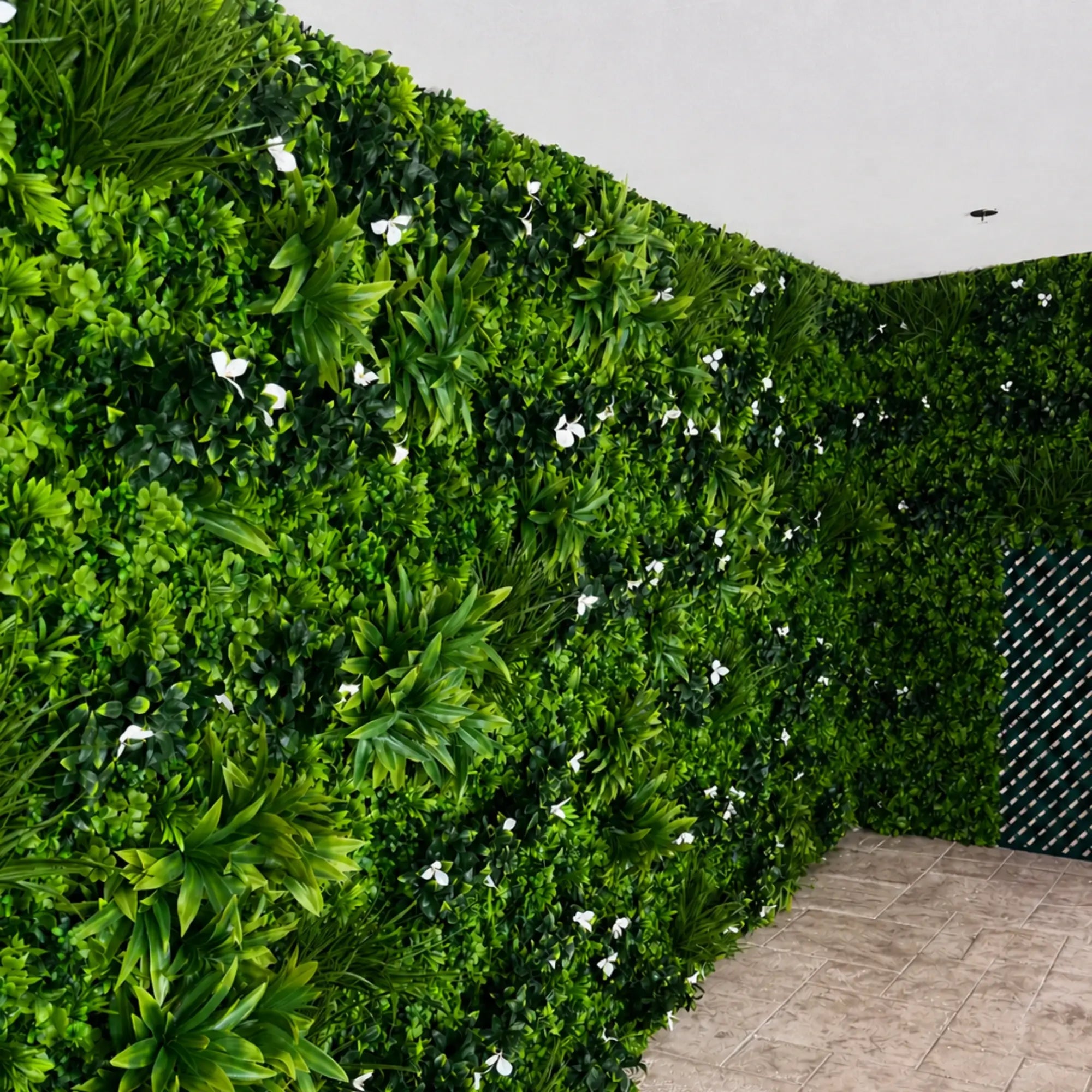 Close-up of Luxury White Oasis artificial vertical garden showing layered green leaves and subtle white flowers for a premium lush wall effect