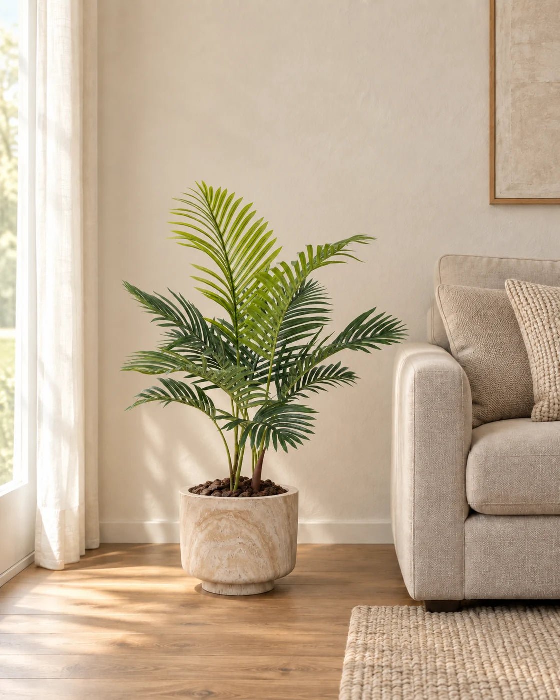 90 cm artificial Areca Palm in a marble-effect pedestal planter beside a linen sofa in a naturally lit living room.