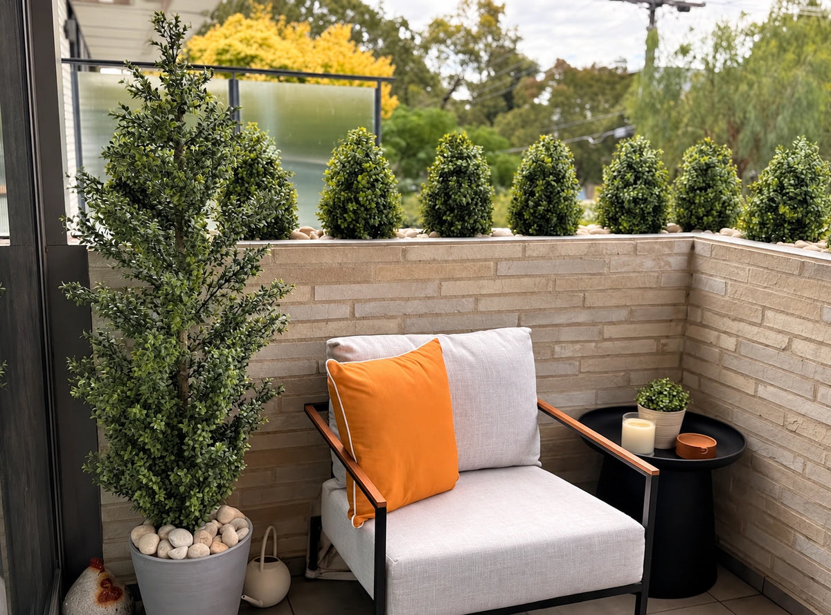 Modern patio chair with orange cushion, potted plants, and side table on balcony.