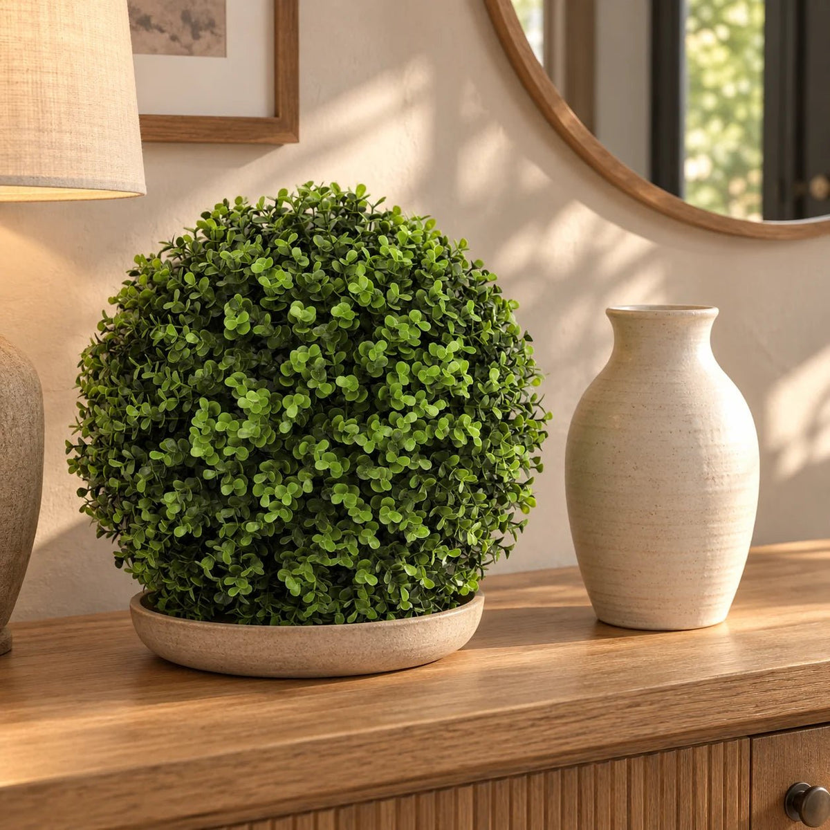 Artificial Buxus topiary ball on a console beside a ceramic vase