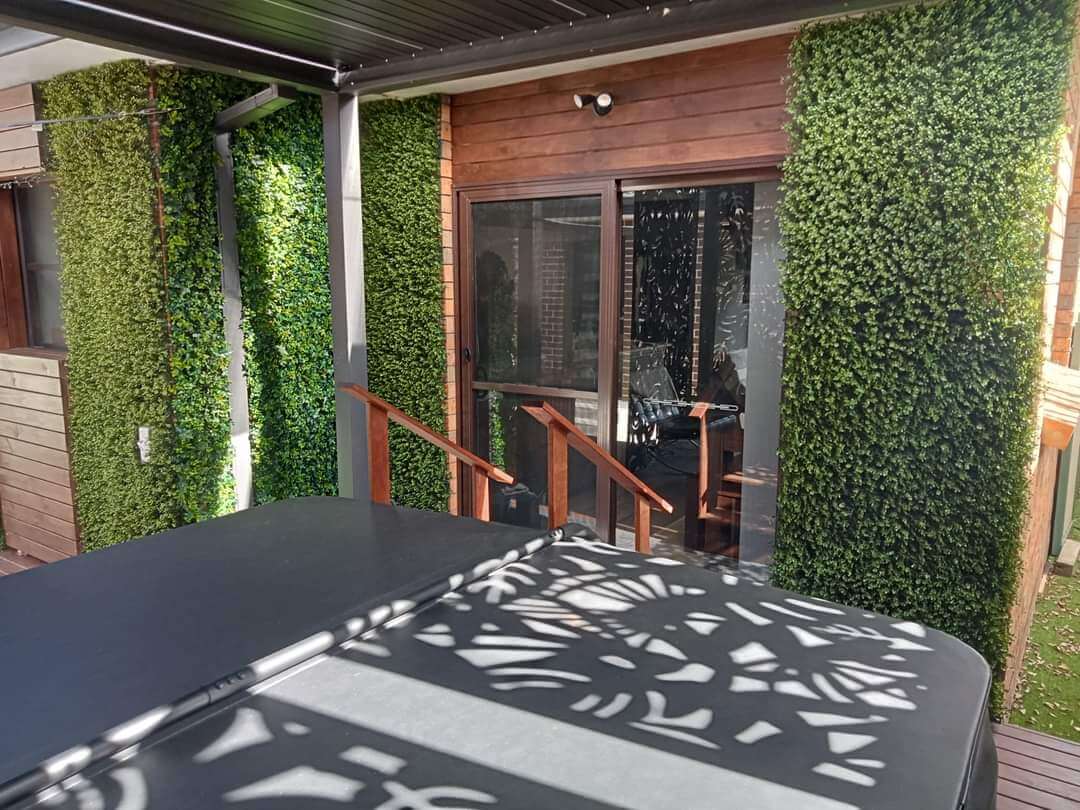 Natural artificial boxwood hedge panel installed onto a deck
