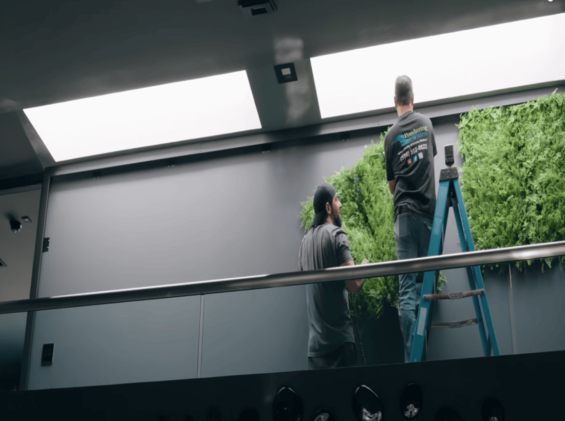Workers installing faux green wall panels indoors modern office interior