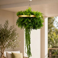 Close-up of a UV resistant artificial green wall disc with a gold frame, featuring dense green foliage and trailing greenery suspended indoors.