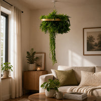 Gold framed artificial green wall disc with lush trailing foliage displayed above a modern beige living room sofa in natural light.