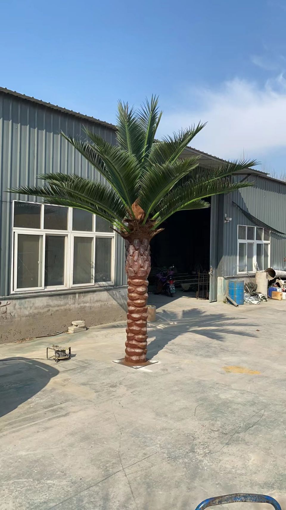 Artificial palm tree in front of a building with a garage door.
