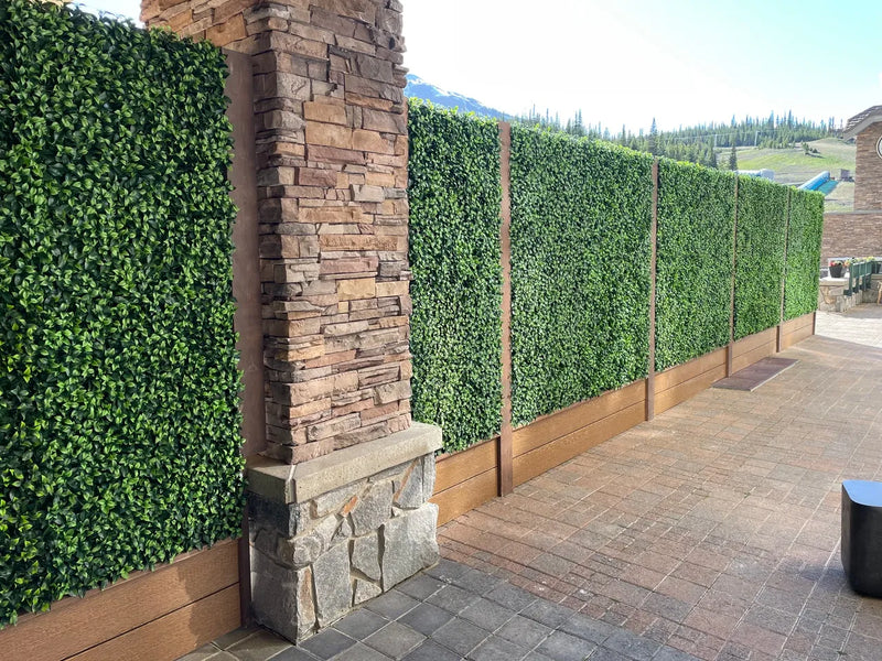 Close-up view of artificial plant wall panels next to a stone pillar.