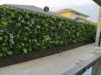Artificial plant wall with diverse green foliage and white flowers by a modern poolside