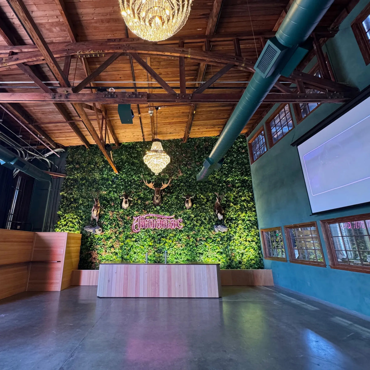 Wide interior view of a luxury commercial venue featuring Amazon Jungle Artificial Vertical Garden Green Wall Panels 40×40in 11 SQ FT UV Resistant Commercial Grade installed as a dramatic floor-to-ceiling greenery backdrop beneath timber ceilings and chandeliers.