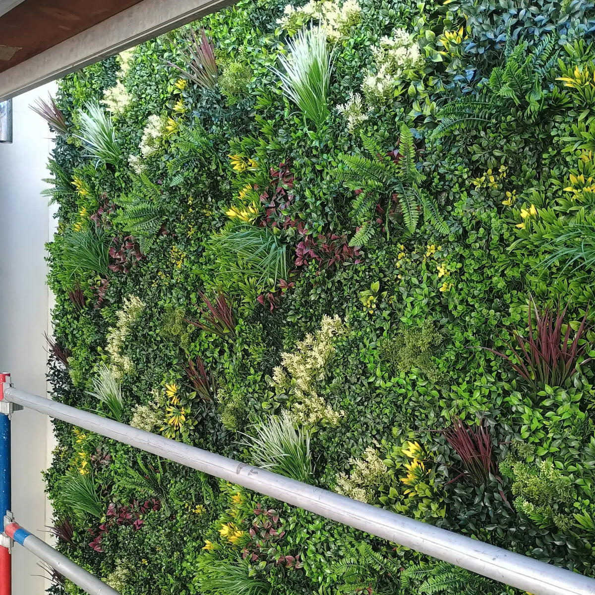 Artificial green wall panel with mixed foliage, vertical garden decor for indoor or outdoor spaces.