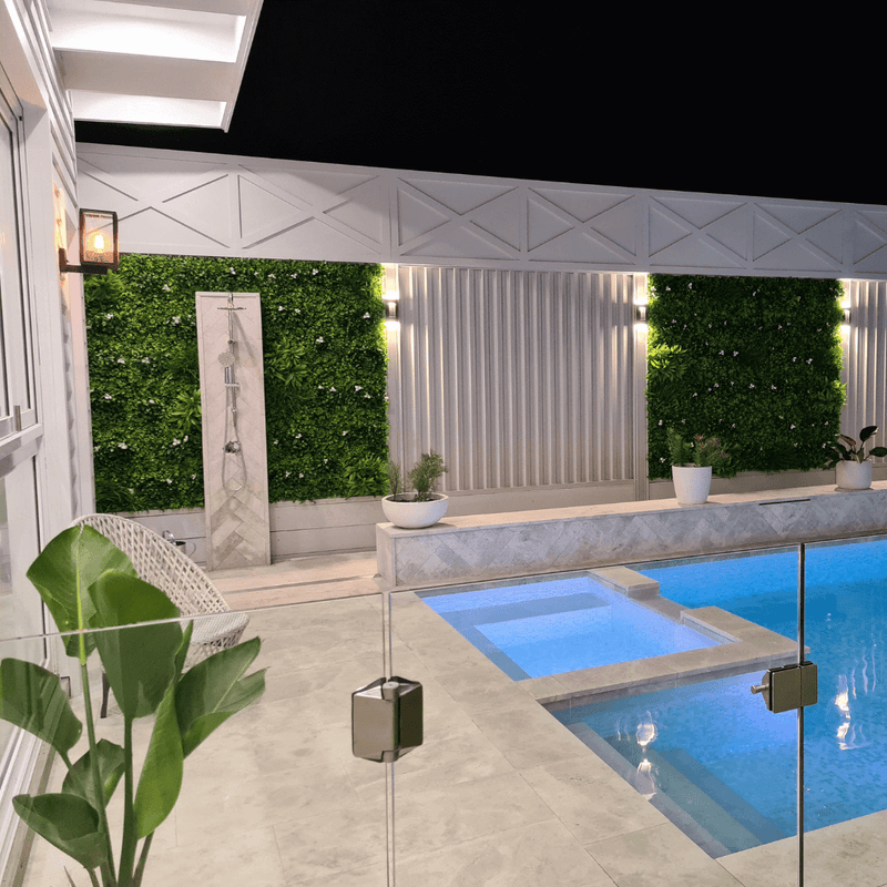 artificial flower wall installed along a pool with lights at night