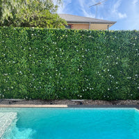 Straight-on view of White Oasis artificial vertical garden panels forming a seamless green wall along a poolside fence, enhancing privacy and outdoor aesthetics.
