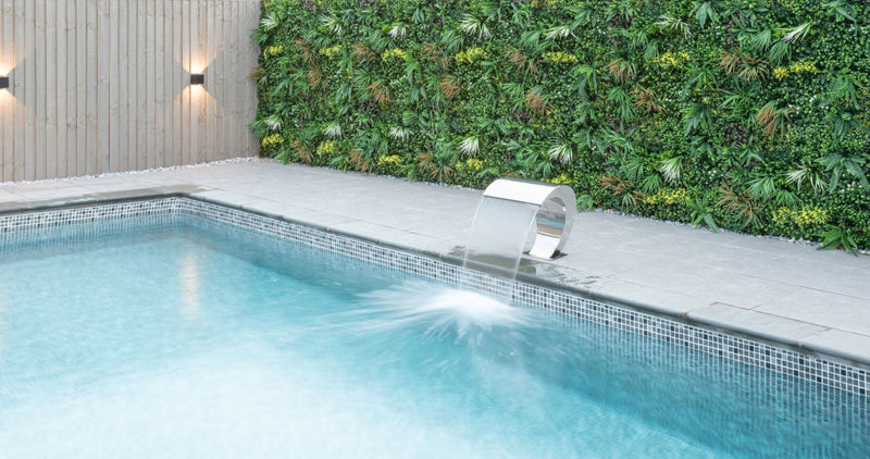 Plastic plant wall panel with foliage along a pool