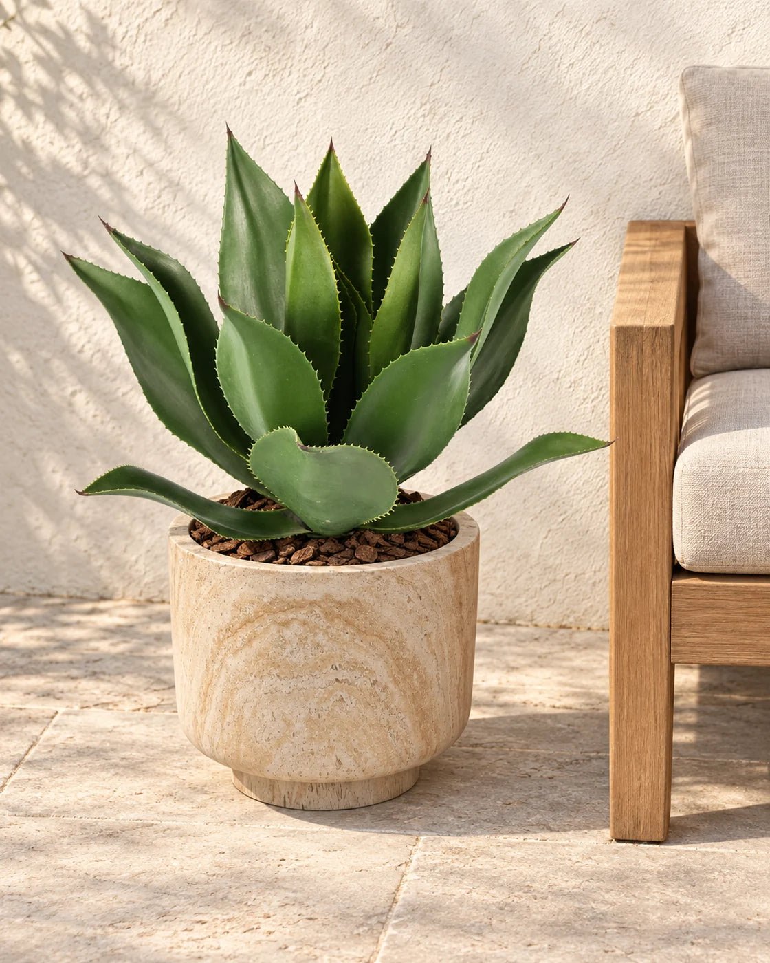 55 cm artificial Agave styled in a marble-effect pedestal planter beside a teak bench on a sunlit patio.