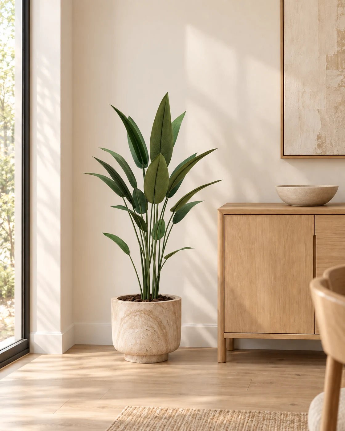 120 cm artificial Bird of Paradise in a marble-effect pedestal planter beside an oak sideboard in a naturally lit interior.