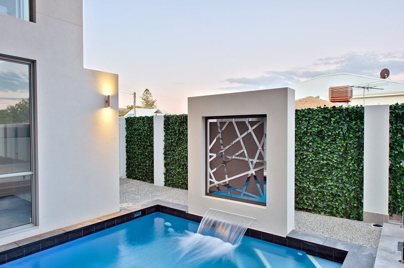 Artificial Ivy Plant Wall Panel Installed along a fence behind a pool