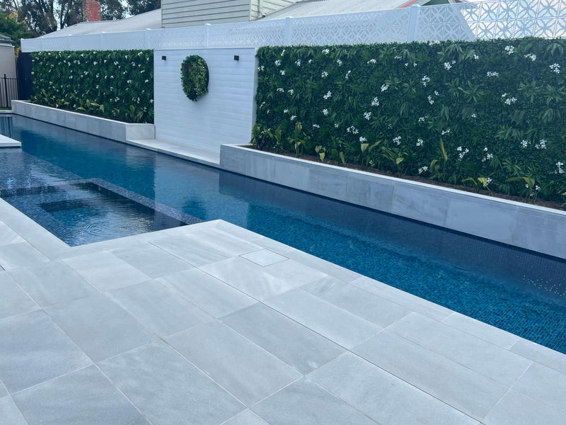 Premium artificial green wall with flowers next to a pool